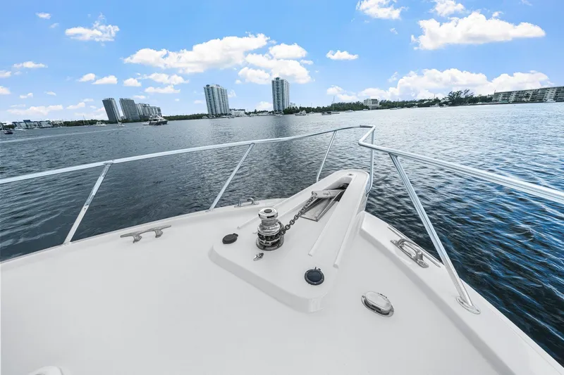 Slide: The Image of Bow view of 2002 Hatteras 60 Convertible yacht on a sunny day, city skyline in background. - 66