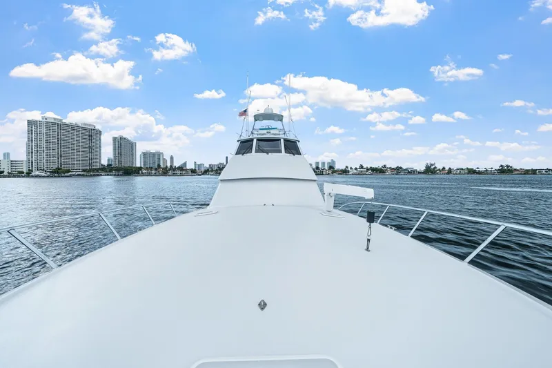 Slide: The Image of 2002 Hatteras 60 Convertible yacht cruising near city skyline under blue sky. - 67