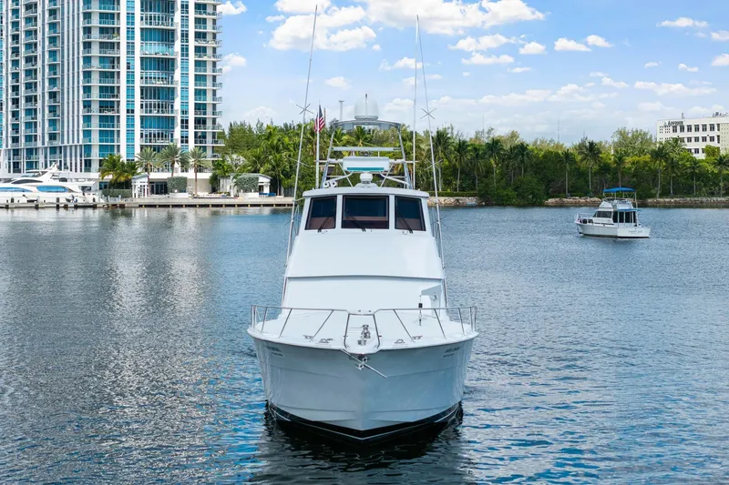 Slide: The Image of 2002 Hatteras 60 Convertible yacht on calm water near modern buildings. - 8