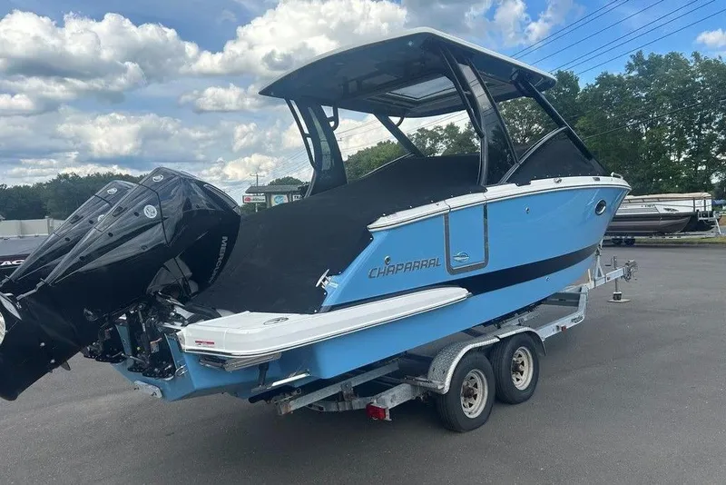 Slide: The Image of 2026 Chaparral 280 OSX boat on trailer, blue exterior, dual engines, parked outdoors. - 13