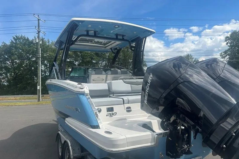 Slide: The Image of 2026 Chaparral 280 OSX boat with dual Mercury engines, parked outdoors under blue sky. - 3