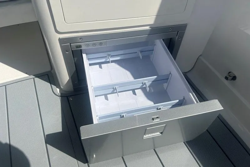 Slide: The Image of Open storage drawer on 2026 Chaparral 280 OSX boat, featuring adjustable dividers. - 52