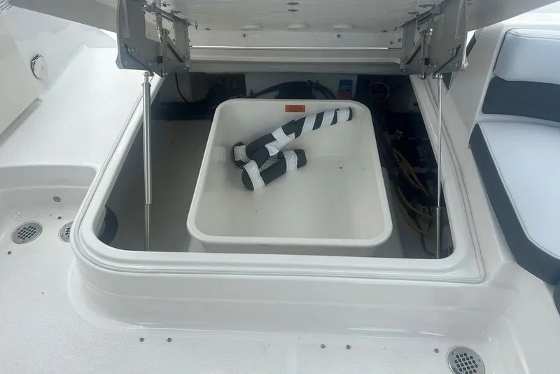 Slide: The Image of Open storage compartment on 2026 Chaparral 280 OSX boat, featuring interior view and accessories. - 69