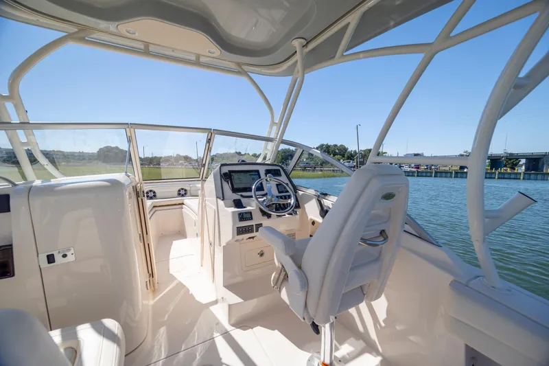 Slide: The Image of 2023 Grady-White Freedom 235 boat interior with helm, steering wheel, and water view. - 12