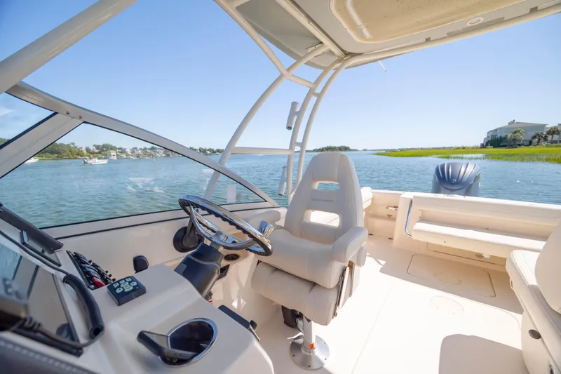 Slide: The Image of 2023 Grady-White Freedom 235 boat interior with steering wheel and scenic water view. - 21