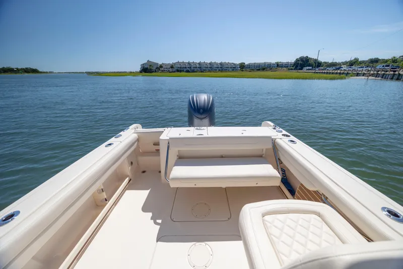 Slide: The Image of 2023 Grady-White Freedom 235 boat on calm water, showcasing spacious seating and scenic view. - 27