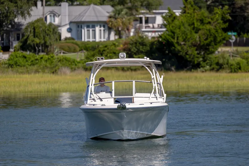 Slide: The Image of 2023 Grady-White Freedom 235 boat cruising on a serene waterway near lush greenery. - 4