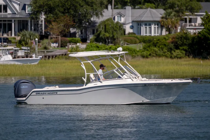 Slide: The Image of 2023 Grady-White Freedom 235 boat cruising on a calm waterway near waterfront homes. - 6