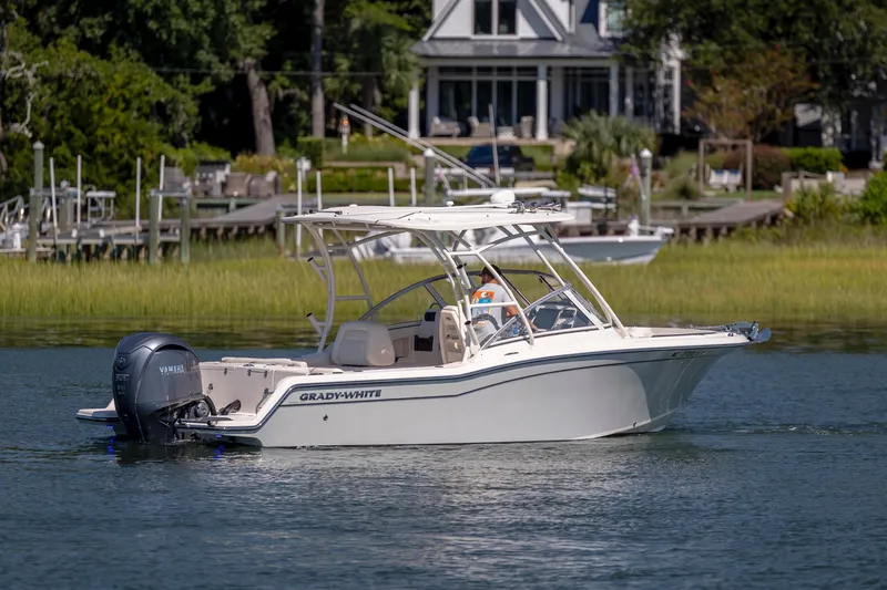 Slide: The Image of 2023 Grady-White Freedom 235 boat cruising on a serene lake near a waterfront home. - 7