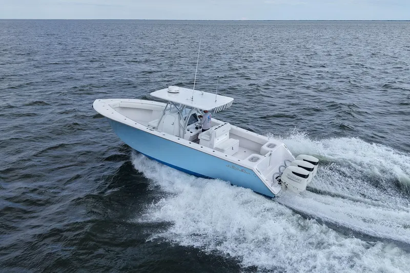 Slide: The Image of 2019 SeaHunter 33 Tournament boat cruising on open water, featuring triple outboard engines. - 38