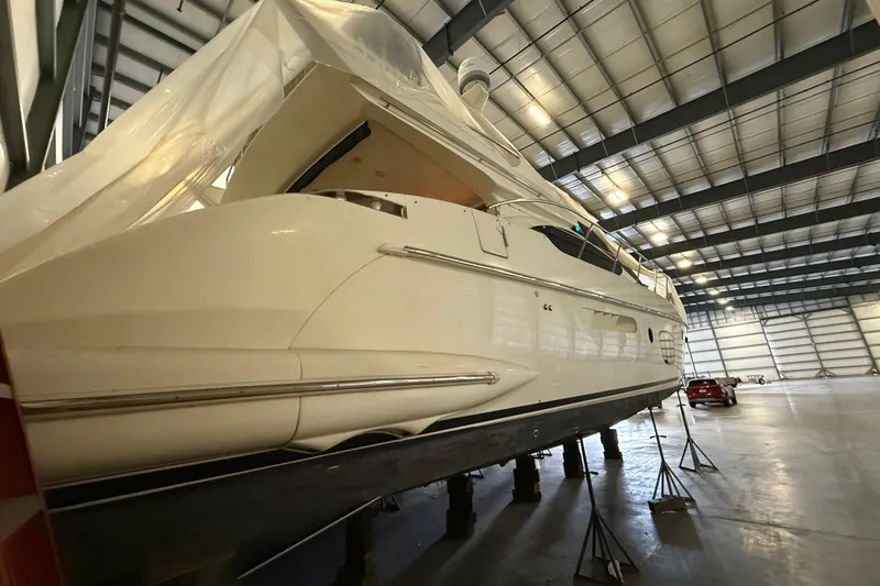 Slide: The Image of 2008 Azimut 55 EVOLUTION yacht in storage, elevated on stands inside a spacious warehouse. - 2