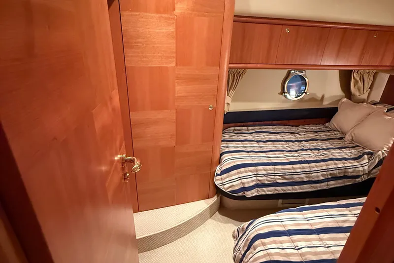 Slide: The Image of Luxurious twin cabin interior on 2008 Azimut 55 EVOLUTION yacht, featuring wood paneling and striped bedding. - 43