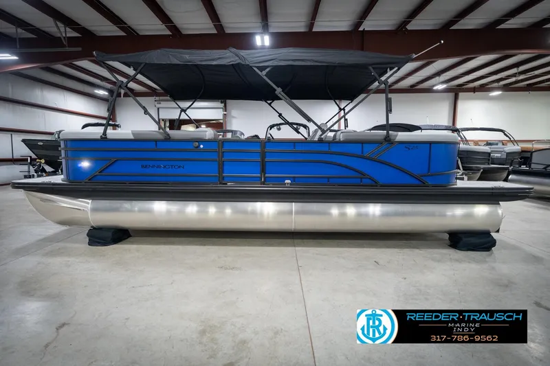 Slide: The Image of 2026 Bennington 25 SSR pontoon boat in showroom, featuring sleek blue design. - 11