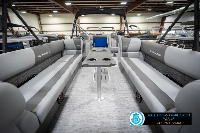 Slide: The Image of 2026 Bennington 25 SSR pontoon boat interior with gray seating and table in showroom. - 16