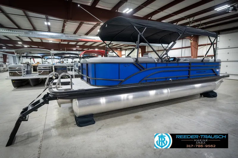 Slide: The Image of 2026 Bennington 25 SSR pontoon boat in showroom, featuring sleek blue design and canopy. - 8