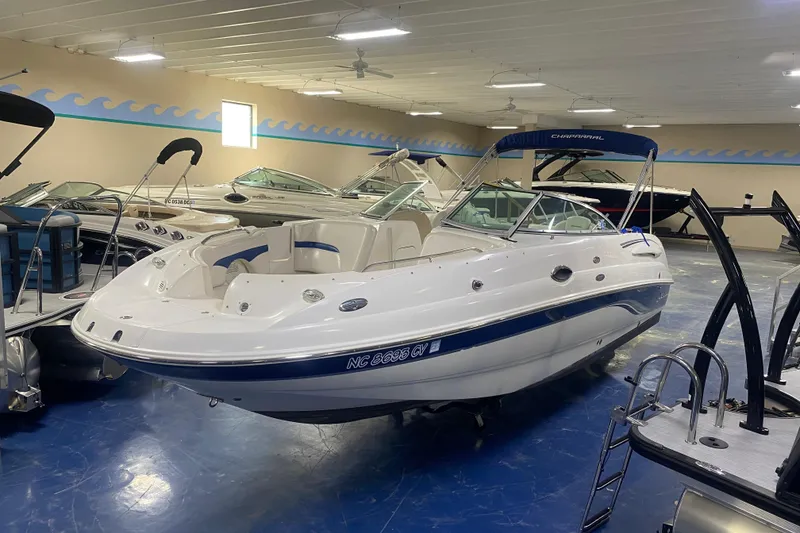 Slide: The Image of 2002 Chaparral Sunesta 243 boat in showroom, white with blue accents, indoor display. - 1