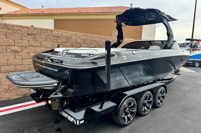 Slide: The Image of 2015 Centurion Enzo FS44 boat on trailer, parked outdoors, showcasing sleek design and triple-axle wheels. - 5