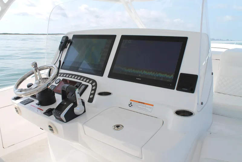 Slide: The Image of 2024 Intrepid 41 Valor helm with dual screens and steering wheel on calm waters. - 19