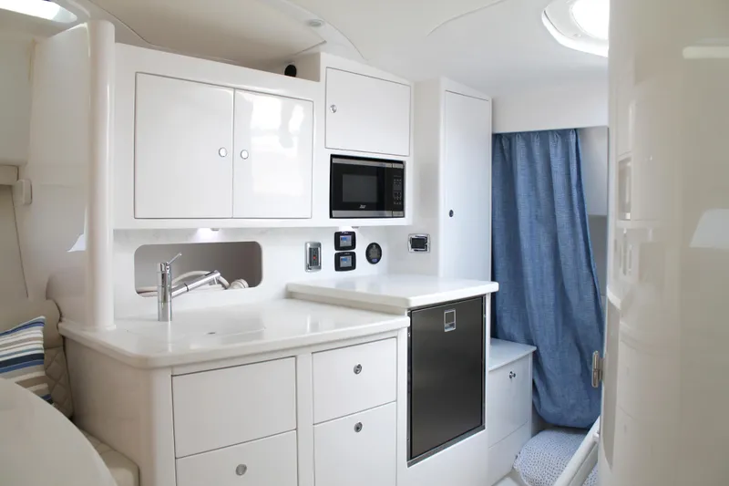 Slide: The Image of 2024 Intrepid 41 Valor yacht interior with modern kitchen, white cabinetry, and blue curtain. - 30