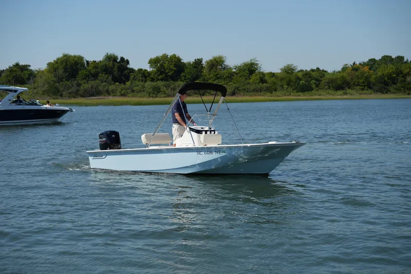 Slide: The Image of 2025 Boston Whaler 170 Montauk boat cruising on a calm lake with trees in the background. - 0