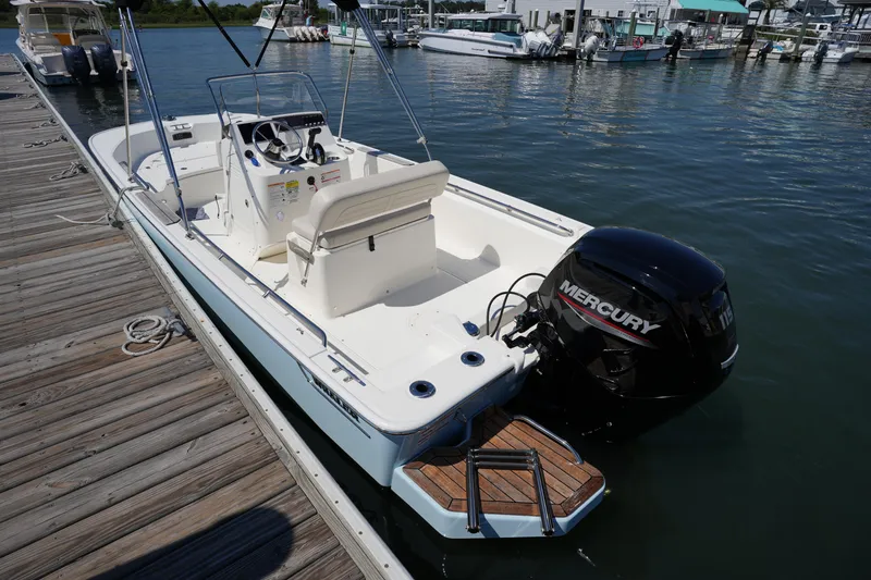 Slide: The Image of 2025 Boston Whaler 170 Montauk boat docked, featuring a Mercury outboard motor. - 10