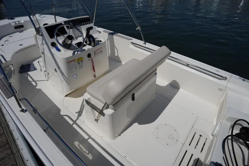 Slide: The Image of 2025 Boston Whaler 170 Montauk boat interior with steering console and seating, docked on water. - 11