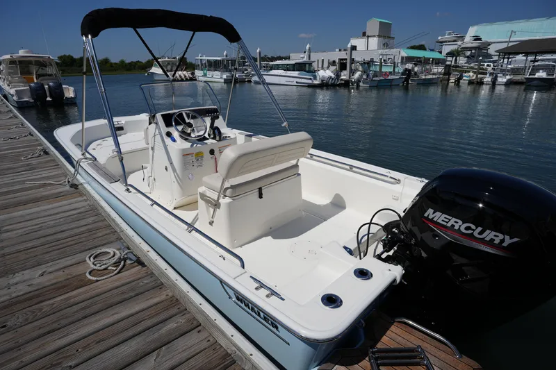 Slide: The Image of 2025 Boston Whaler 170 Montauk boat docked with Mercury engine, sunny marina setting. - 25