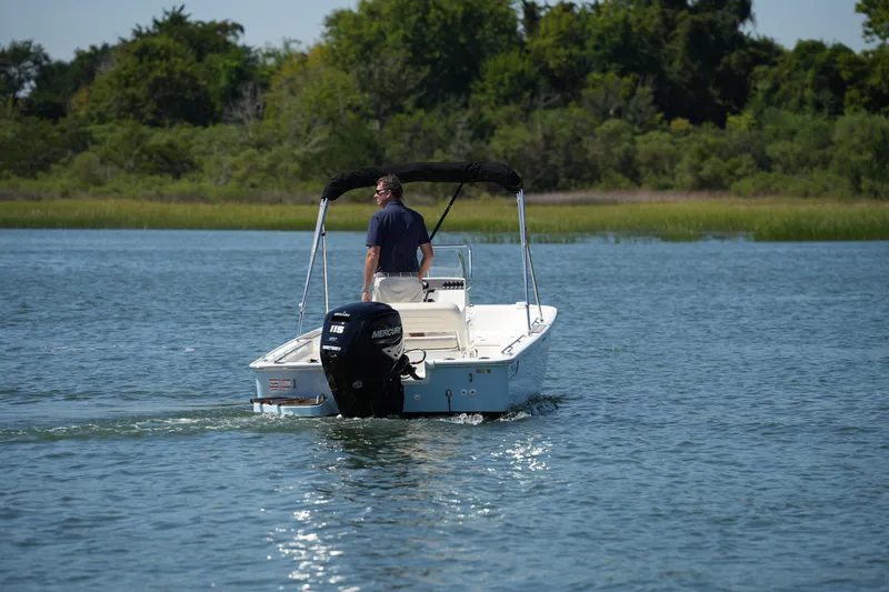 Slide: The Image of 2025 Boston Whaler 170 Montauk cruising on a serene lake with lush greenery. - 9