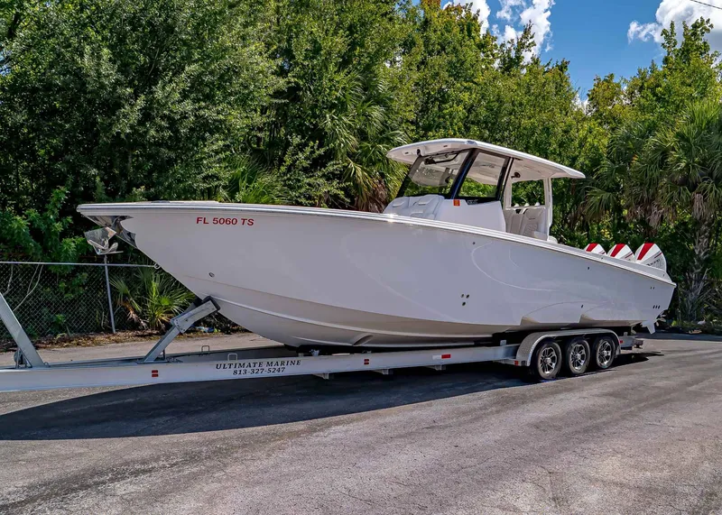 The Image of 2024 Fountain 32 NX boat on trailer, parked outdoors with lush greenery background. - 1