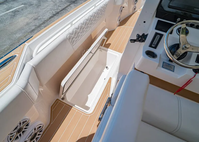 Slide: The Image of 2024 Fountain 32 NX boat interior with open storage compartment and steering wheel. - 14