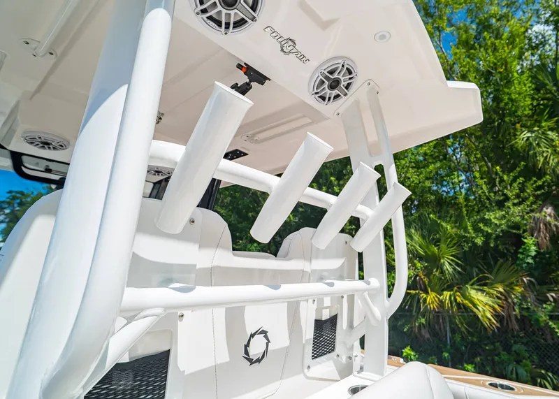 Slide: The Image of 2024 Fountain 32 NX boat with rod holders and speakers, set against a lush green backdrop. - 19