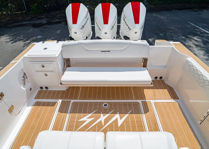 Slide: The Image of 2024 Fountain 32 NX boat interior with triple outboard engines and teak flooring. - 9