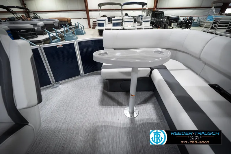 Slide: The Image of 2026 Bennington 20 SL pontoon boat interior with seating and table in showroom. - 18