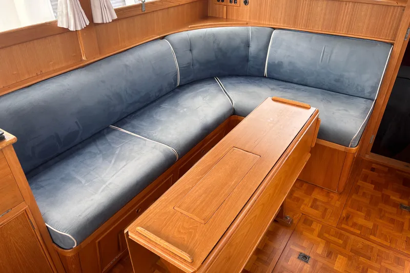 Slide: The Image of Cozy seating area in 1991 Grand Banks 36 Classic yacht with wooden table and blue cushions. - 15