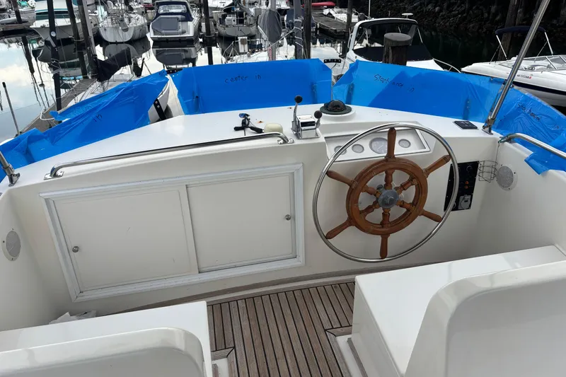 Slide: The Image of 1991 Grand Banks 36 Classic yacht helm with wooden wheel, docked in marina. - 2