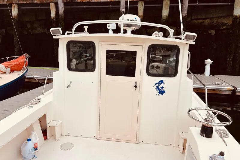 Slide: The Image of 2001 Parker 2520 Deep Vee Sport Cabin boat docked, featuring a white cabin and steering wheel. - 20