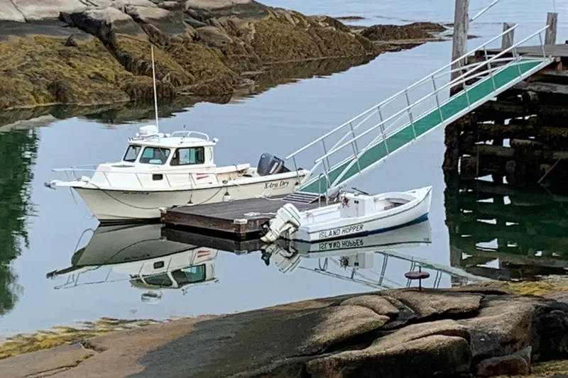 Slide: The Image of 2001 Parker 2520 DVSC boat docked beside a small dinghy in a serene harbor. - 3