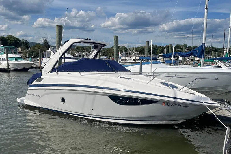 The Image of 2023 Regal 28 Express boat docked in a marina under a partly cloudy sky. - 0