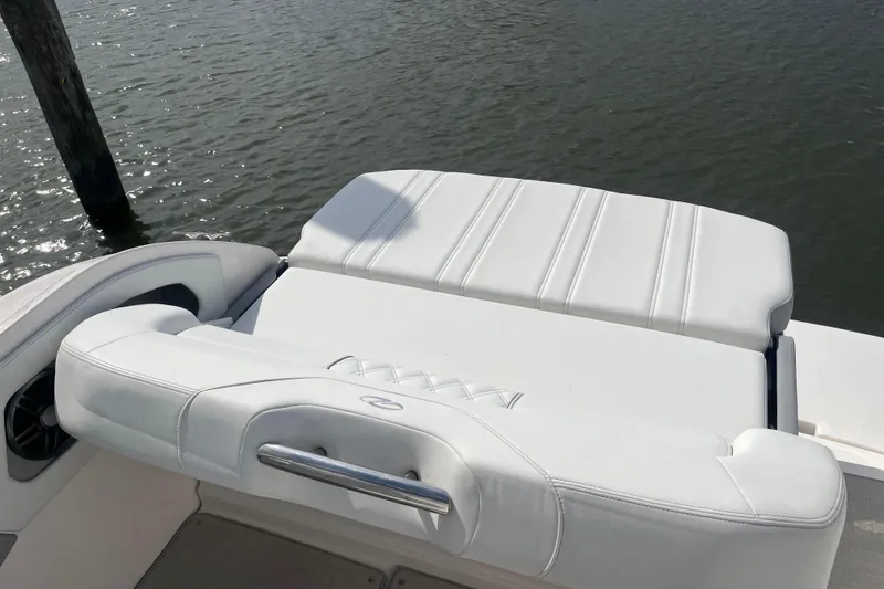 Slide: The Image of 2023 Regal 28 Express boat with white cushioned seating by the water. - 13