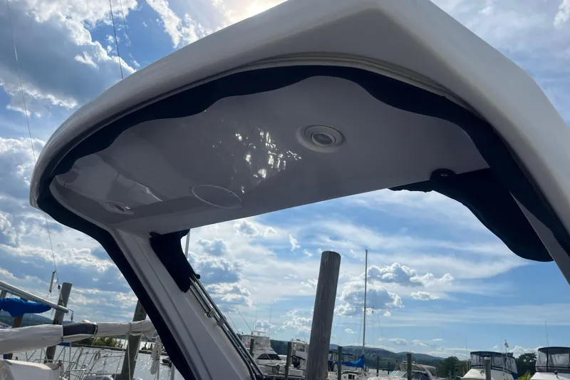 Slide: The Image of 2023 Regal 28 Express boat canopy under a bright, partly cloudy sky at a marina. - 36