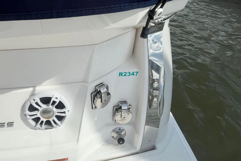 Slide: The Image of 2023 Regal 28 Express boat stern with speaker and chrome fittings near water. - 7