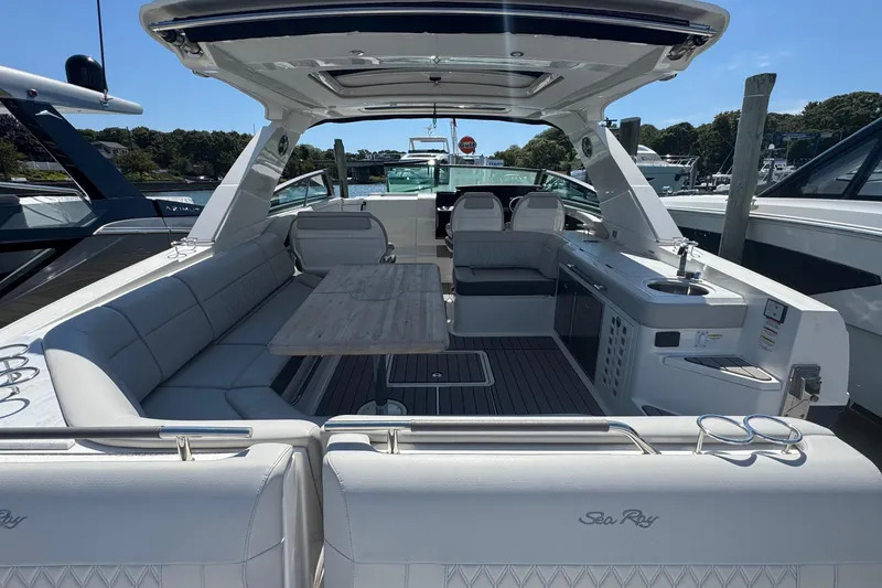 Slide: The Image of 2023 Sea Ray SLX 400 Outboard boat interior with seating and table, docked at marina. - 14