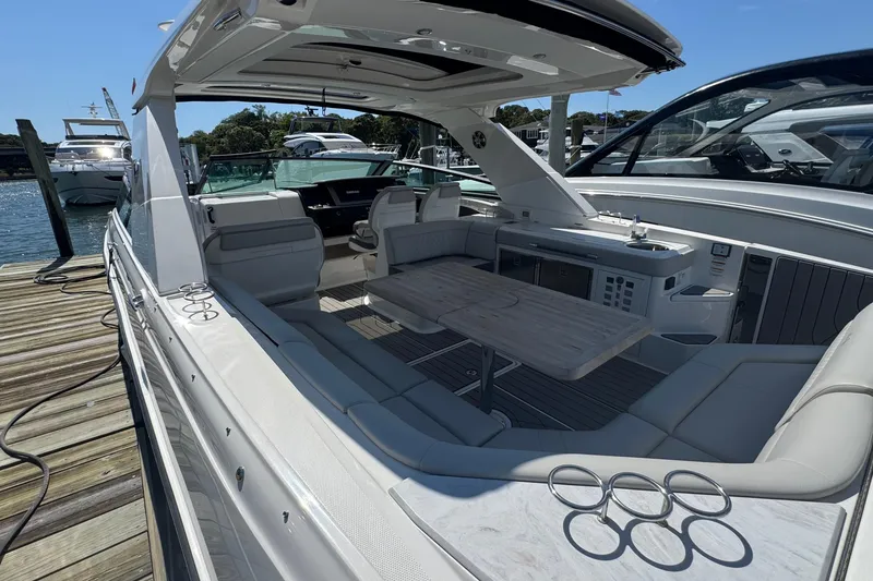Slide: The Image of 2023 Sea Ray SLX 400 Outboard luxury boat interior at dock, featuring spacious seating and table. - 15