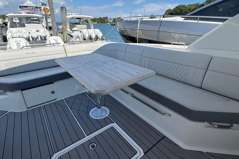 Slide: The Image of 2023 Sea Ray SLX 400 Outboard boat interior with seating and table, docked at marina. - 19