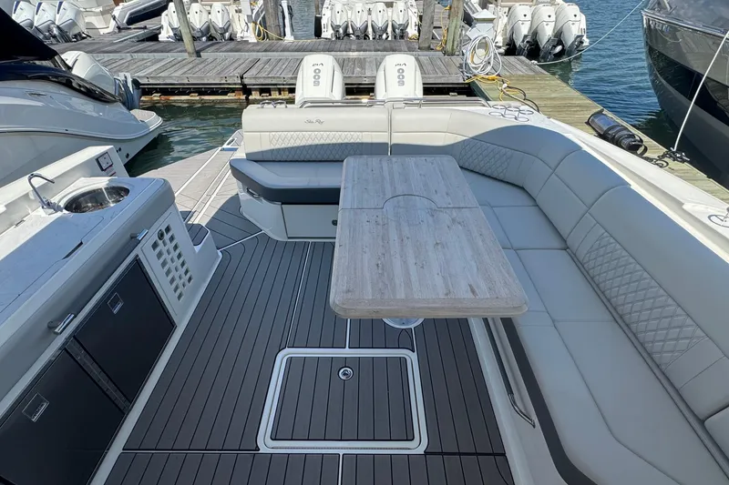 Slide: The Image of 2023 Sea Ray SLX 400 Outboard boat interior with seating and table, docked at marina. - 20