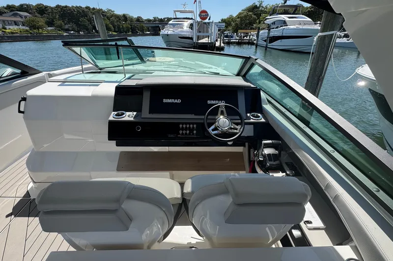 Slide: The Image of 2023 Sea Ray SLX 400 Outboard helm with Simrad display, docked near luxury yachts. - 23