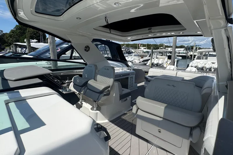 Slide: The Image of 2023 Sea Ray SLX 400 Outboard luxury boat interior at marina, featuring plush seating. - 29