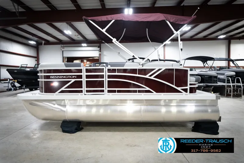 Slide: The Image of 2026 Bennington 168 SLJ pontoon boat in showroom with maroon canopy and sleek design. - 11
