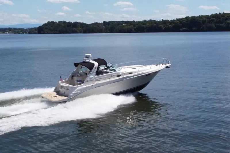 The Image of 1995 Sea Ray 330 Sundancer cruising on a serene lake under a clear sky. - 0
