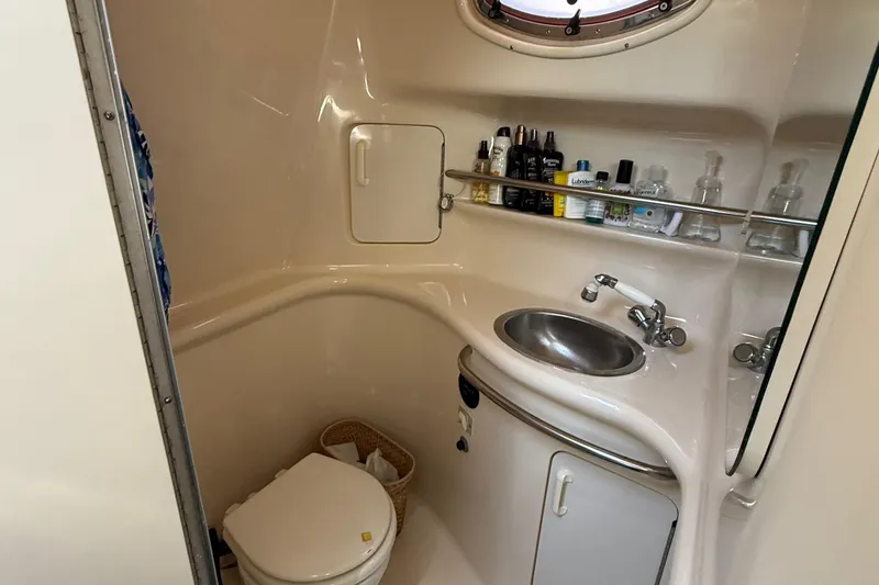 Slide: The Image of 1995 Sea Ray 330 Sundancer bathroom with sink, toilet, and toiletries on shelves. - 17